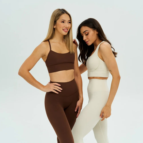 two women wearing black and white leggings and sports bras